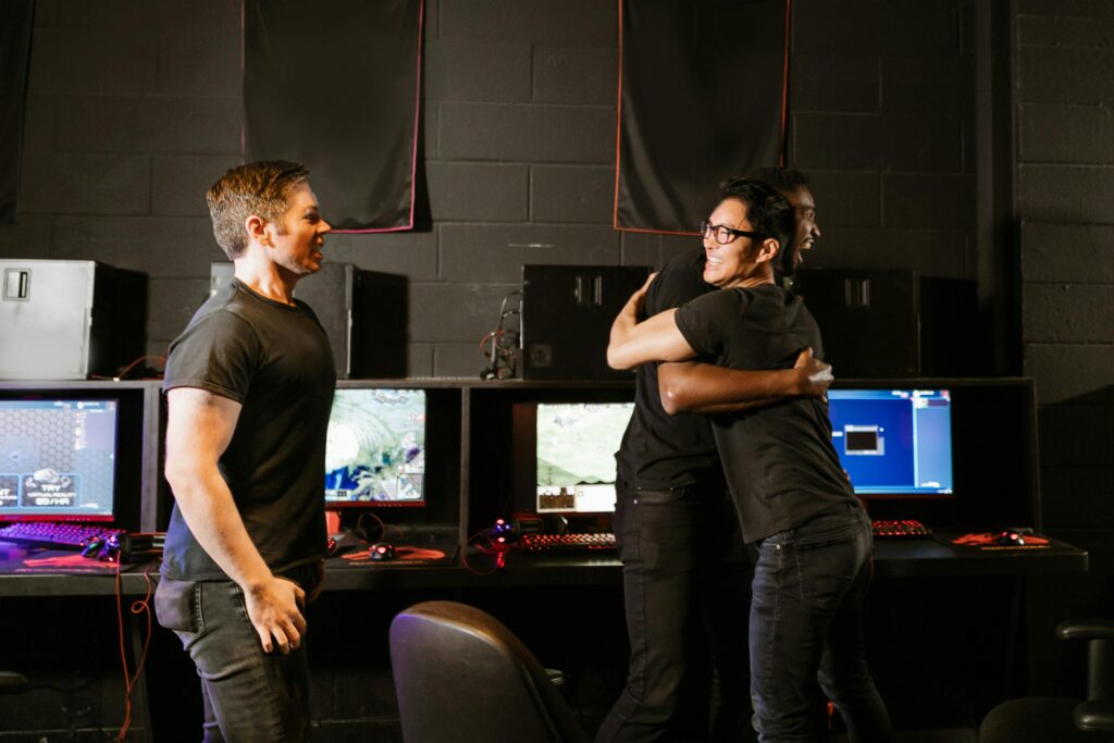 Young men celebrate a gaming win together in an eSport cyber cafe, exuding happiness and camaraderie.
